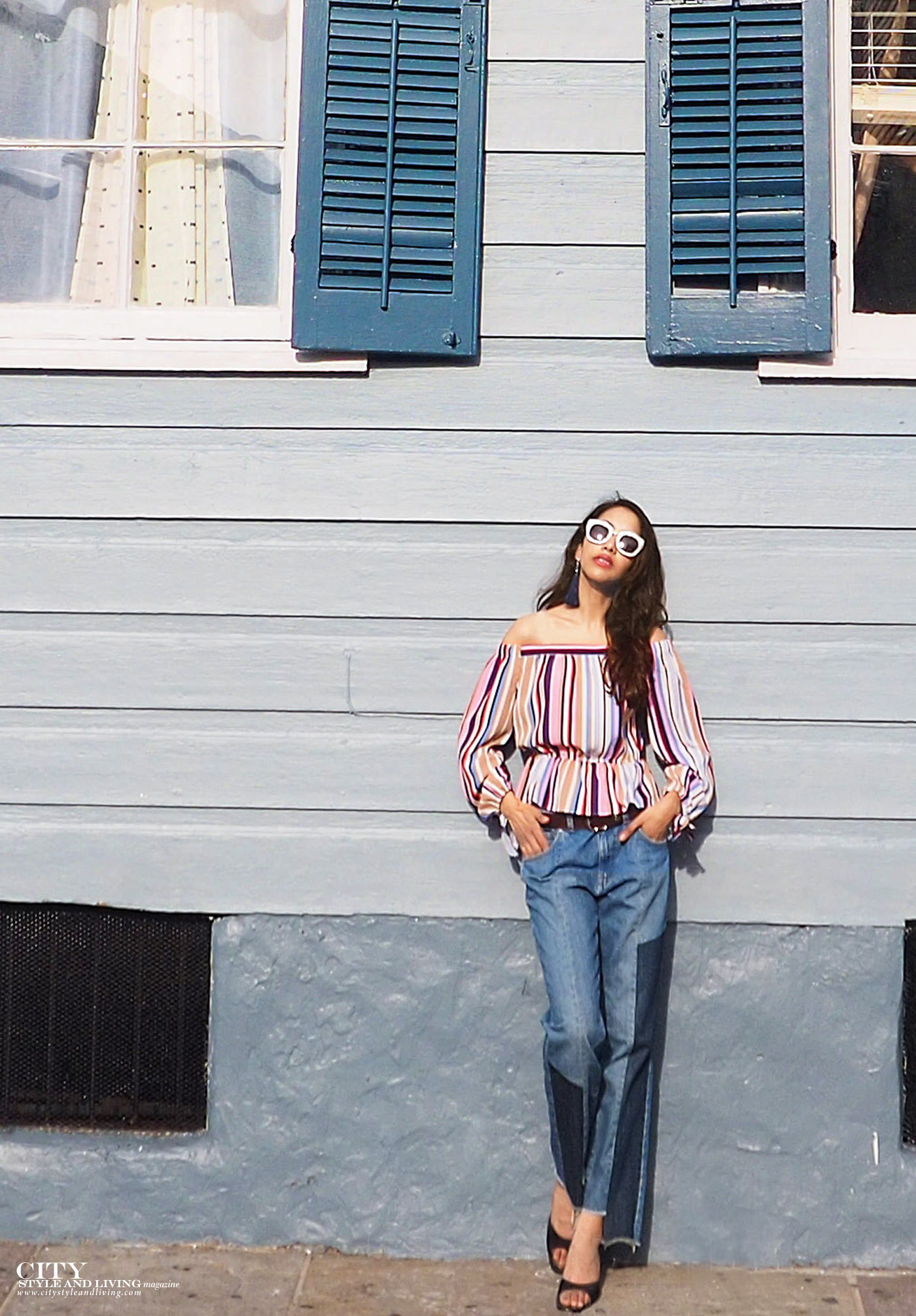 City style and living magazine The Editors Notebook style fashion blogger Shivana Maharaj New Orleans French Quarter Off shoulder top and ankle biter jeans standing by blue house