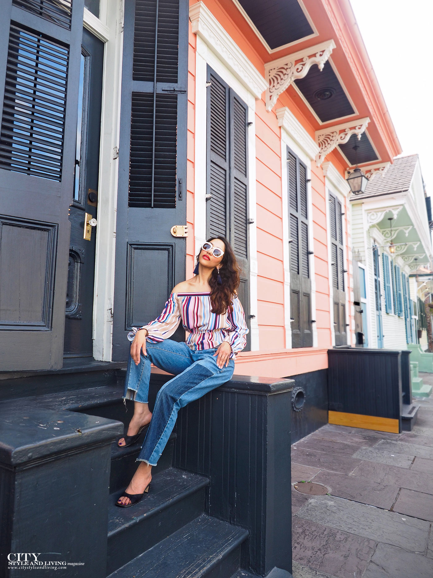 City style and living magazine The Editors Notebook style fashion blogger Shivana Maharaj New Orleans French Quarter Off shoulder top and ankle biter jeans sitting by colourful houses